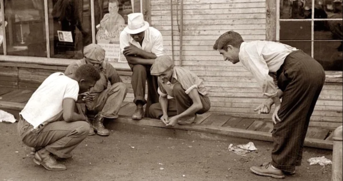 People playing street dice on the sidewalk.